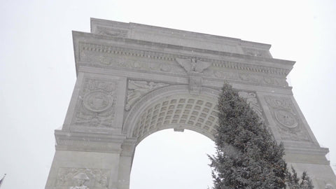 beautiful winter day snowing Christmas tree under Washington Square Park arch NYC