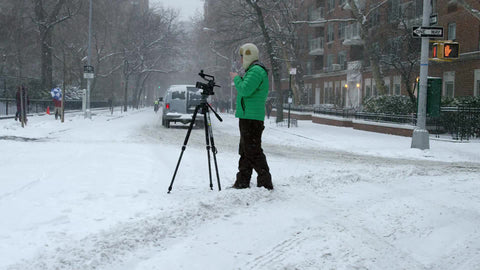 photographer filming with camera and tripod in winter blizzard - snowing on Washington Square Park North - snow in NYC