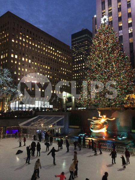 people in ice skating rink in Rockefeller Center with Christmas tree lit up - winter holidays at night