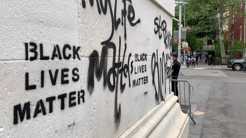Black Lives Matter graffiti on stone wall of Washington Square Park arch with NYPD cops New York City NYC