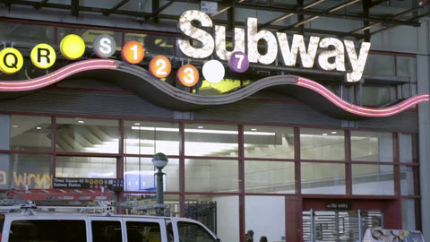 big exterior subway station sign off Times Square in Manhattan at night