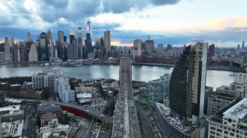 aerial following Brooklyn Bridge to American flag and Manhattan skyline East River in NYC