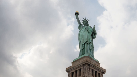 Statue of Liberty on base with bright sunny sky and clouds moving fast - 4K upward angle timelapse in New York City