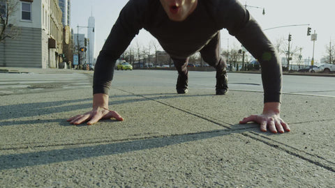 man doing pushups on Manhattan's westside with Freedom Tower in background on sunny fall day
