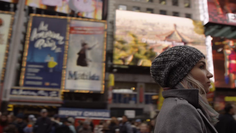 circling lost tourist looking up at overwhelming bright lights and signs in Times Square cold winter - pretty girl with hat in 4K slow motion