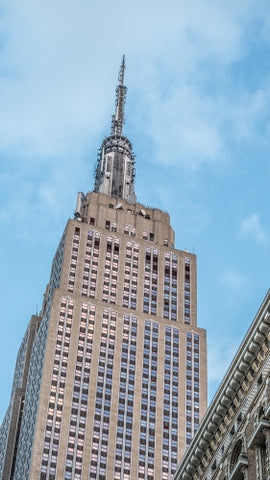 Empire State Building over bright blue summer sky - close-up famous skyscraper in Manhattan