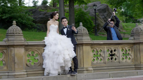 photographer setting up tripod in Central Park for wedding of beautiful couple