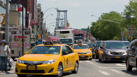 cars and taxi cabs coming off Williamsburg Bridge into Manhattan on summer day in heavy traffic on the Lower East Side in NYC