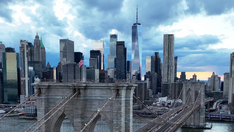 slow close up aerial American flag Brooklyn Bridge Manhattan skyline