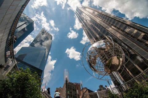 famous globe sculpture and Trump International Tower and Hotel viewed from upward angle from subway station at Columbus Circle on sunny day with bright blue sky