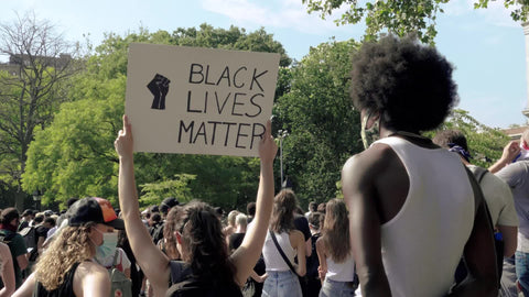 Black man with afro standing by Black Lives Matter sign in New York City BLM rally