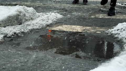 people stepping over puddle in slushy snow winter blizzard New York City