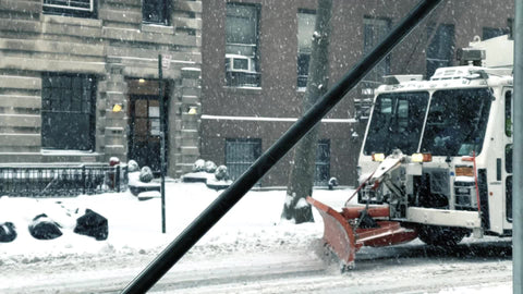 snow plow on garbage truck in storm pushing snow in winter blizzard - snowing in New York City NYC