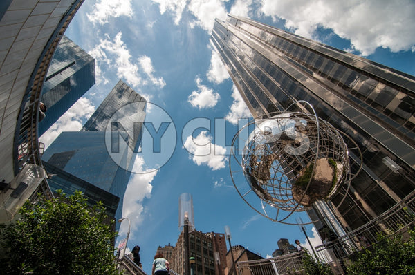 famous globe sculpture and Trump International Tower and Hotel viewed from upward angle from subway station at Columbus Circle on sunny day with bright blue sky