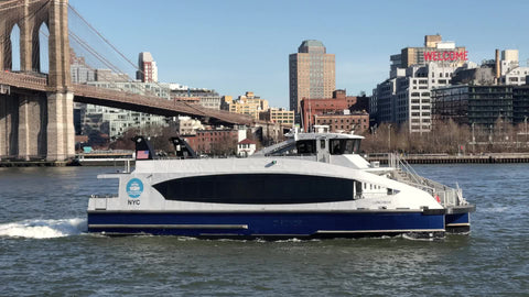 NYC Lunchbox ferry tour boat for kids on East River passing Brooklyn Bridge and Welcome sign in BK New York City