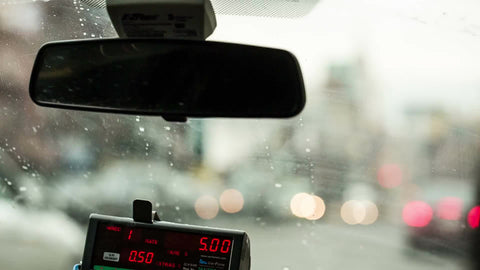 taxi cab driving on Houston Street with Empire State Building view in windshield - rearview mirror and meter in front seat