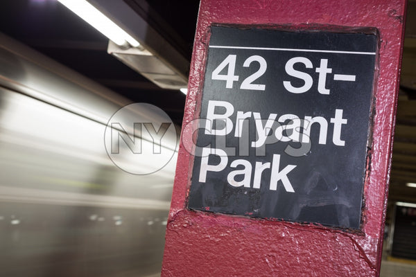 subway column sign for 42nd st and Bryant Park on platform with motion blur train leaving station