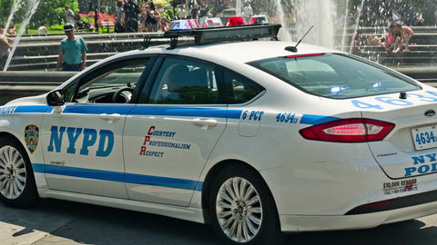 police car driving through Washington Square Park on bright summer day in NYC