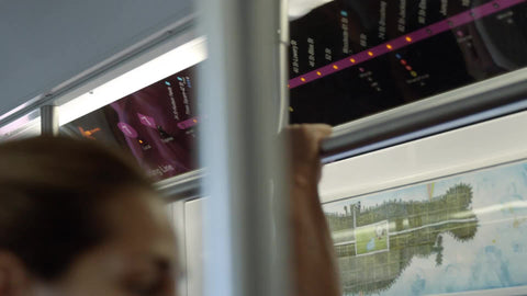 map of stops on 7 train, woman standing on crowded subway, closeup of pole