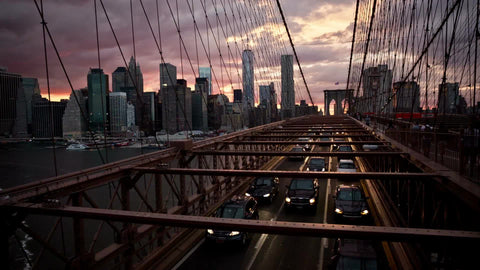 view over cars driving in traffic on Brooklyn Bridge at beautiful sunset in realtime in NYC