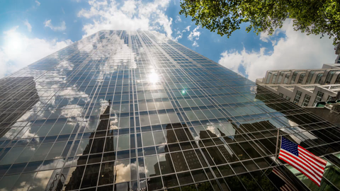 towering glass skyscraper in Manhattan with American flag - 4K timelapse in New York City