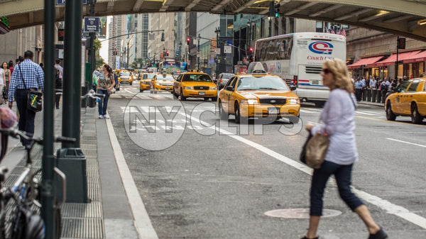 woman crossing street in Midtown outside Grand Central Station with taxi cabs driving in Manhattan