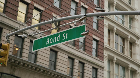 Bond street sign with sneakers hanging from traffic light in NYC