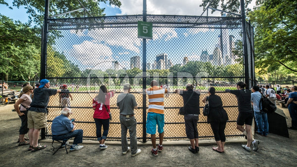 baseball field in Central Park with people watching through fence behind home plate on summer day