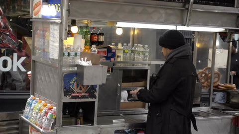 man counting money behind food cart on cold winter day