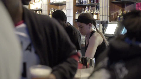 bartender pouring bottle of beer into glass at bar