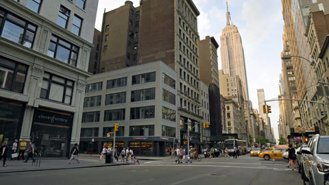 approaching intersection on Lower 5th Avenue with people crossing street, busy crosswalk in summer with Empire State Building in 4K and 1080 HD in Manhattan NYC
