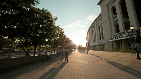 Yankee Stadium exterior at sunset in summer - couple walking by front entrance in the Bronx NYC