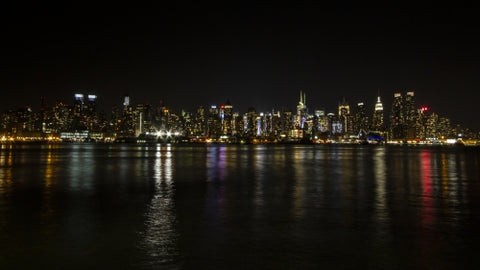 Manhattan skyline at night with reflections off water New York City NYC