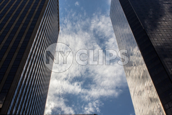 two corporate office buildings - glass windows with reflections of sky and clouds