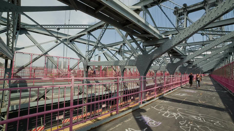 inside view of Williamsburg Bridge with people crossing toward Brooklyn on summer day in NYC