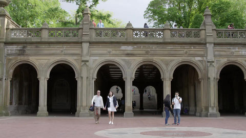 couple holding hands in summer walking from Bethesda Terrace arches in Central Park