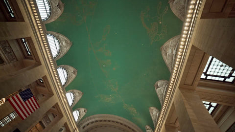 busy Grand Central Station Terminal interior with people walking around in large room with American flag on wall in NYC
