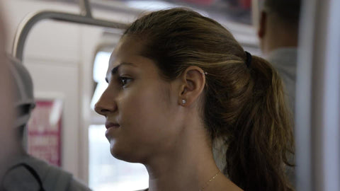 closeup of woman - beautiful face - riding subway, standing on crowded 7 train