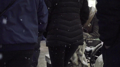 people ignoring homeless man in wheelchair on the street - snowing at night in winter