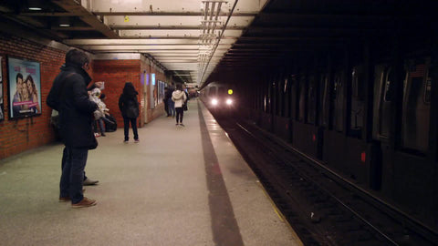 R train entering subway station in slow motion - people on platform