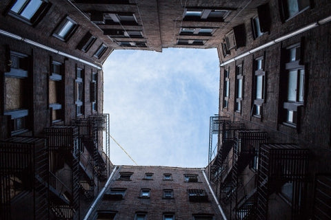 upward angle from city courtyard between 4 buildings looking up at sky