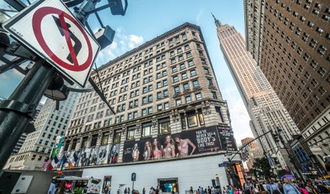 Empire State Building towering over Herald Square on 34th Street on summer day in Manhattan with no lefthand turn sign