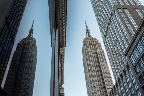 Empire State Building reflection in Midtown glass window during day - towering skyscraper in Manhattan NYC