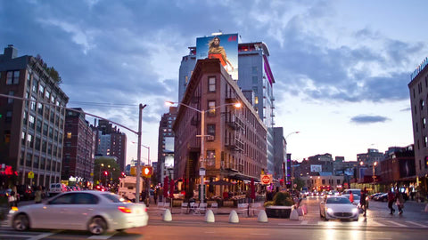Meatpacking District in early evening with cars driving by corner and people crossing street