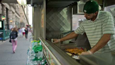 Middle-Eastern man preparing - cooking kabobs in Halal food truck outside on summer day
