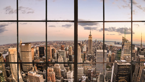 Manhattan cityscape view of Empire State Building tilting down from interior window terrace - 4K at sunset