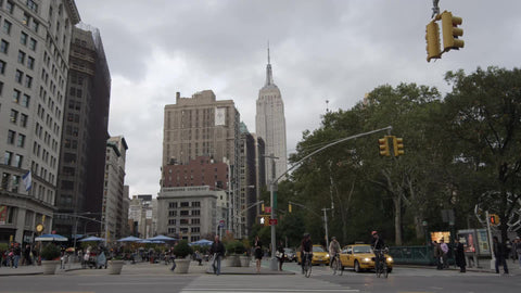 Empire State Building view from Madison Square Park on cloudy fall day with taxis and bicycles in NYC