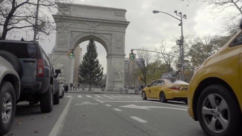 low angle of Washington Square Park on cloudy winter day with Christmas tree underneath arch, taxi cabs driving by