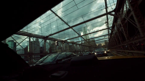 view out backseat - rear windshield of taxi cab driving across Brooklyn Bridge on cloudy day in NYC
