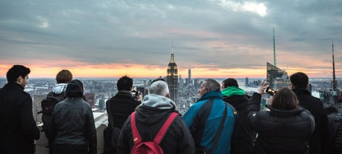 tourists taking photo of Empire State Building in Manhattan observation deck at sunset NYC